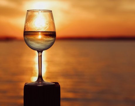 Photo of a wine glass on top of a pier facing the sunset and water of Buckeye Lake.