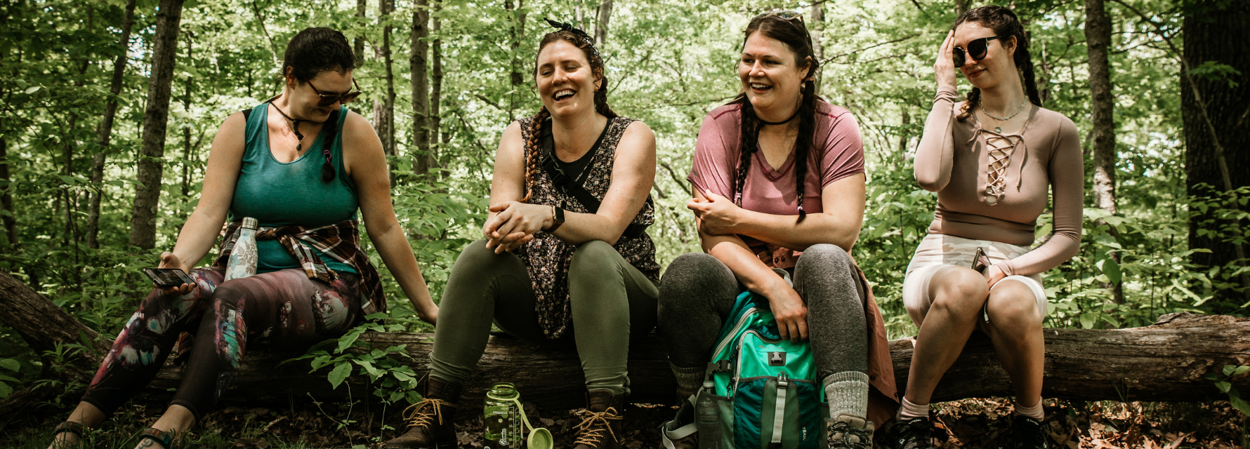 4 girls sitting on a log in the woods