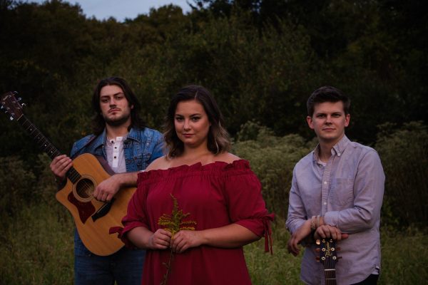 A band standing in a field with their guitars.