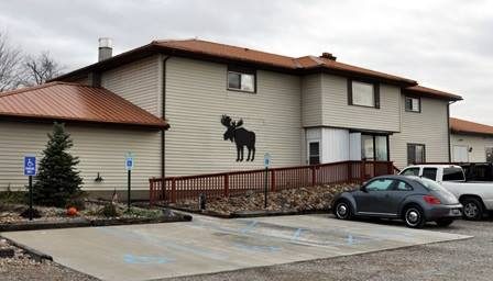 The Moose Lodge; a large, tan building with a silhouette of a moose on the side of the building.