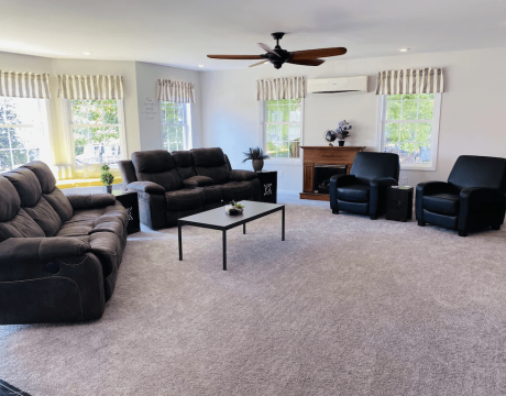 A spacious living room with lots of natural light featuring two couches, a coffee table, and some chairs.