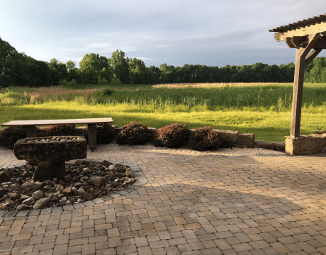 A large firepit and bench beside a large, grassy field.