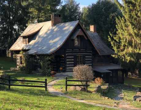 A charming, fenced-in cottage surrounded by trees.