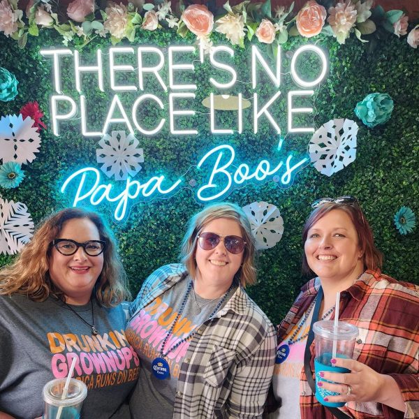 Photo of three women posing in front of a sign that says "There's no place like Papa Boo's"