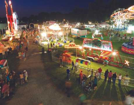 Aerial shot of festival rides and vendors at night.