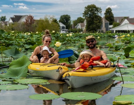 Photo of a family kayaking among lily pads.