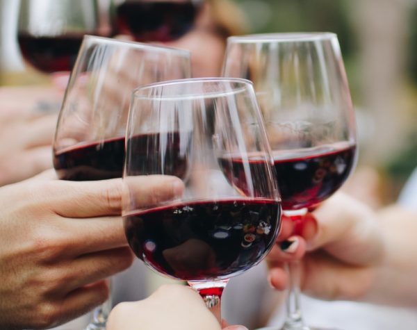 Photo of three people clinking wine glasses.