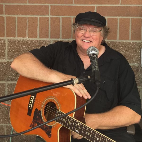 Photo of musician Reid Coleman smiling with a guitar.