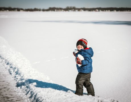 Photo of a small child collecting snowballs.