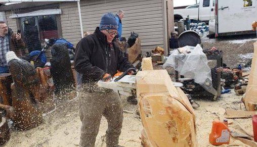 Photo of a man cutting a large block of wood with a chainsaw at Port Smokehouse during Winterfest.