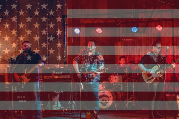 The band Hillbilly Deluxe performing on stage with an image of the American Flag over the band