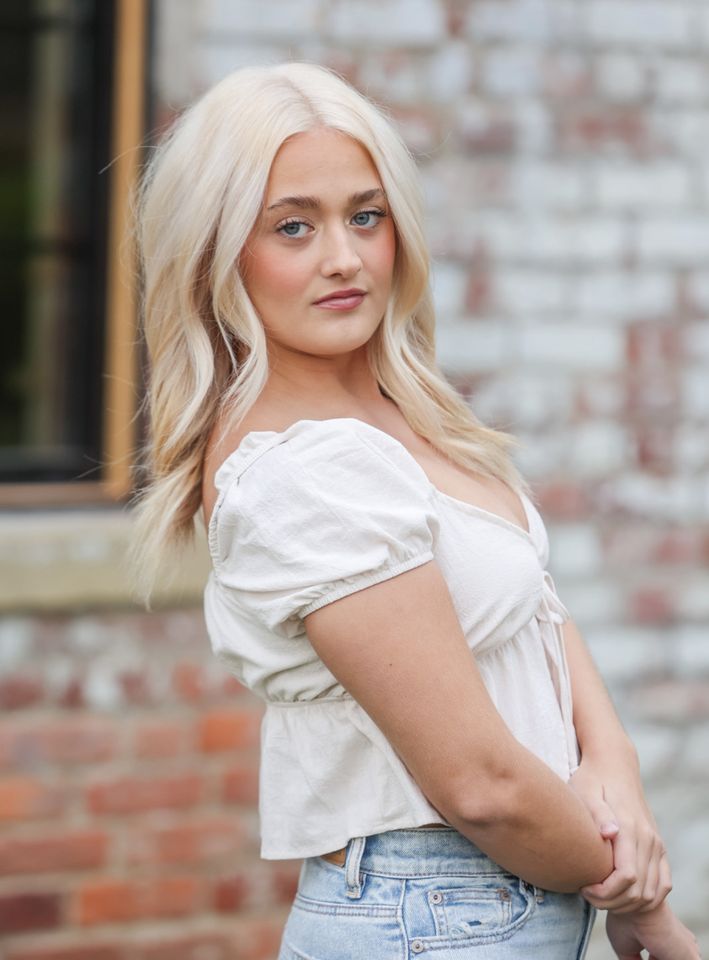 Photo of musician Cali Morris posed in front of a brick background.