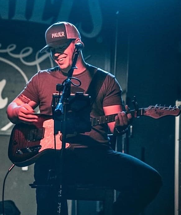 Photo of musician Just Angelo singing and playing guitar