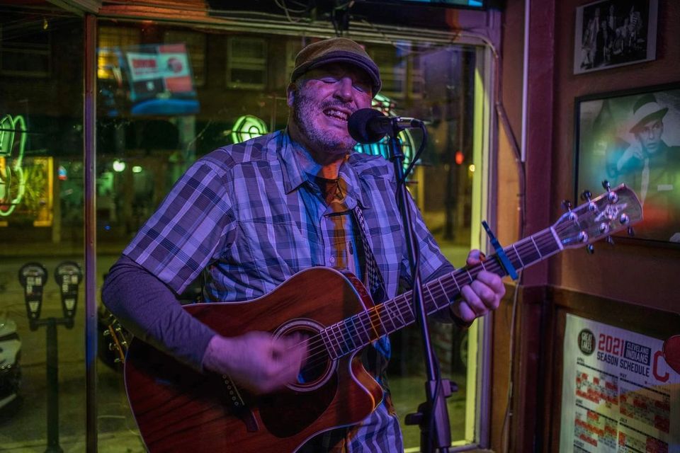 Musician from Lower Case j singing and playing guitar.