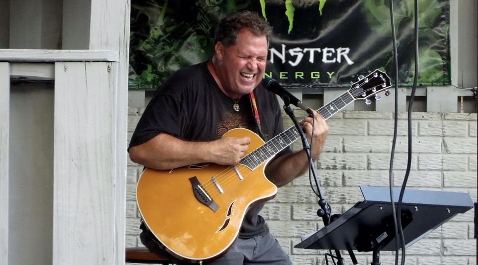 Photo of musician Pete Mernedakis singing and playing guitar