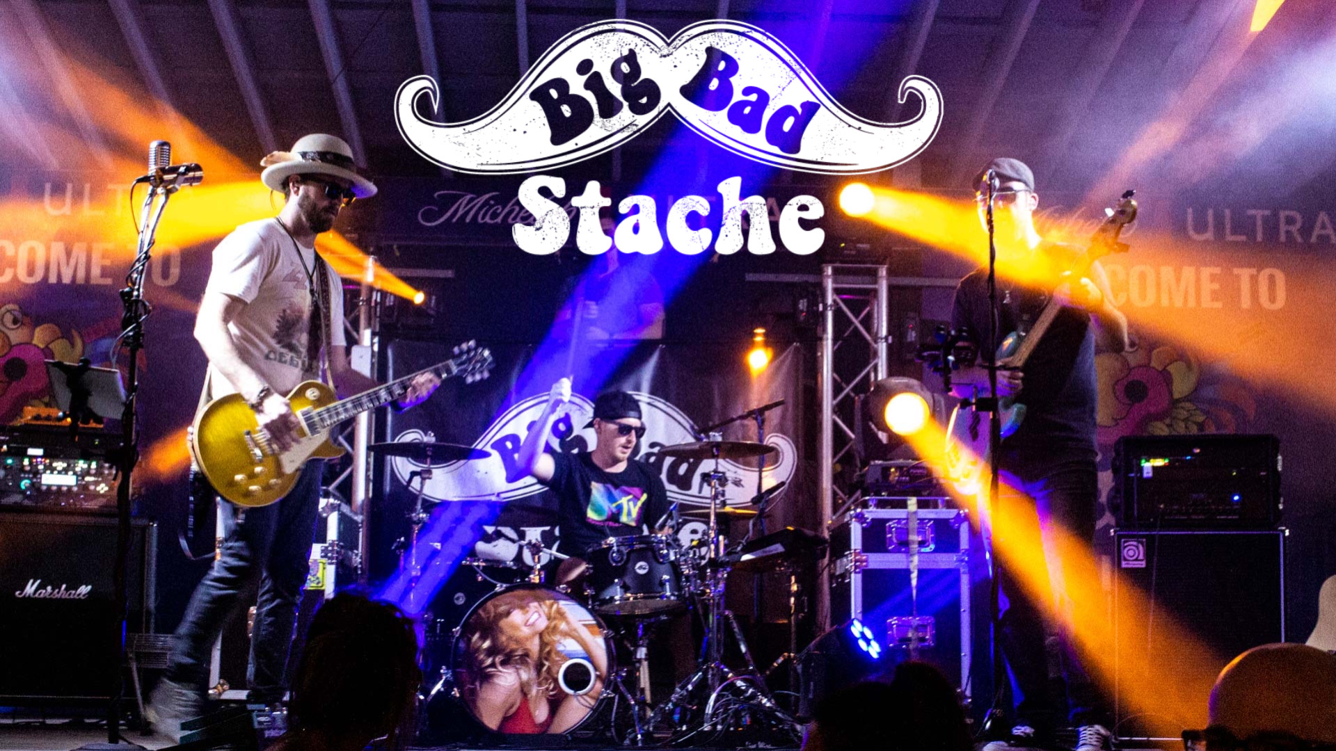 Photo of the Big Bad Stache band and their moustache logo.