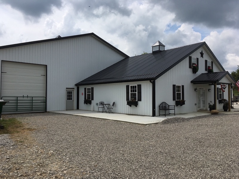 A white pole barn with gravel parking lot.