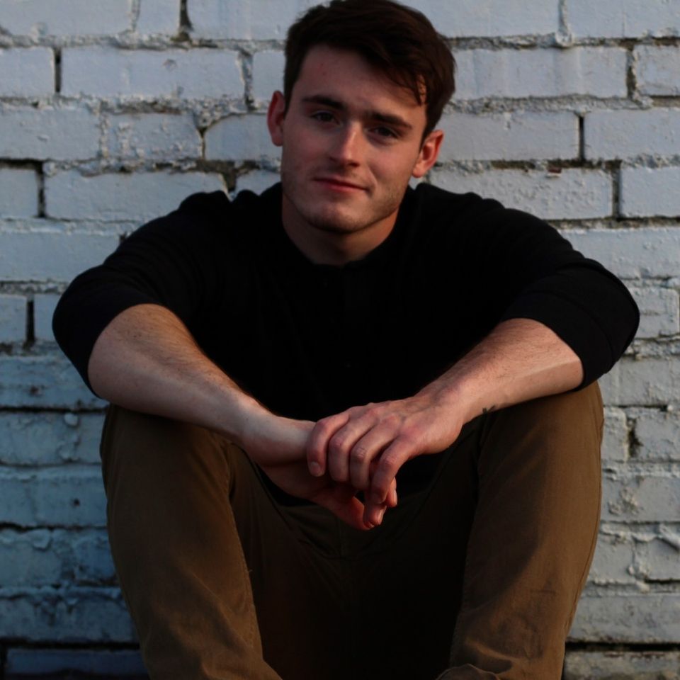 Photo of musician Austin Finley posed in front of white brick