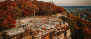 A large cliff overlooks a city in the fall.